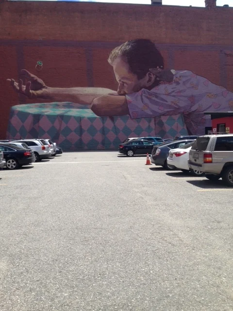 a mural on the outer edge of the neighborhood frames a parking lot