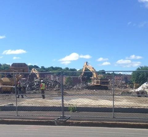 Compare Dino's solo building of the patio with the cataclysmic pace of development of the hockey rink down the street. One hallmark of a "Robert Moses" type project is the clear cutting of large tracts of land for a single use facility. Sniff out where the bulldozers are most active! This summer, this whole city block was cleared to make room for the new hockey rink venue.