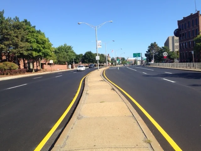 I waited to see where the painted lane lines would go. Guess what? The lines were still in the very same place they were before the road was re-done! It still remains a six lane "freeway" right in the downtown -- so wide that it remains difficult to cross on foot and unsafe to traverse on a bicycle. Some questions: DPW, where is the community input on how the road was re-designed? Where is the imagination of what this road could have become and how it could have been re-designed to work for everyone - car drivers, walkers, bus riders, bicyclists? Also, check out the median strip made completely of desolate-looking concrete. Wouldn't walkers be more enticed if we added grass or plantings here? If we want to have more pedestrian activity, we need to create a more aesthetically appealing experience for people who prefer to walk. 
