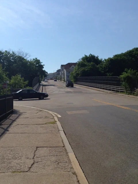 The highway now functions as a subtle barrier between the triple-decker housing stock on the hill and the commercial district below. Although sidewalks grace both sides of the highway overlook, the highway still becomes a psychological and even physical divider of the space.