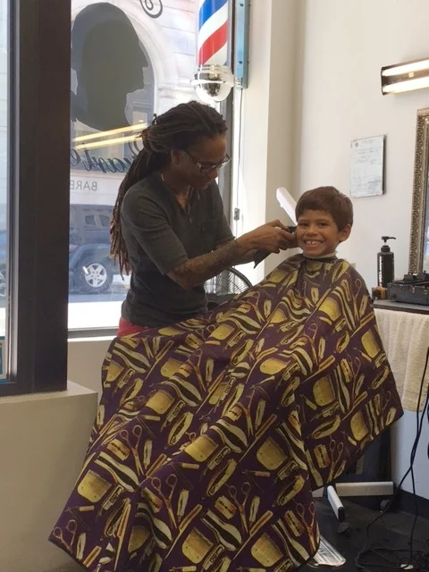For the past four years, Jahaira Gomez invested in growing her Head Quarters barbershop on Portland Street. She will be forced to move in August and believes she may have to relocate to another city that is supportive of her enterprise. A customer in the store warns, "The big fish are coming here and pushing out the little fish."