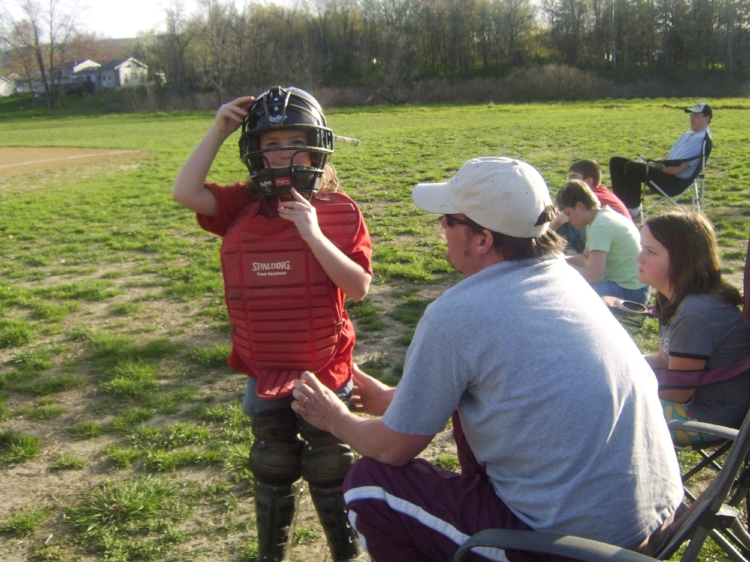 Brian helps Natalie ready for her catcher position in town softball.