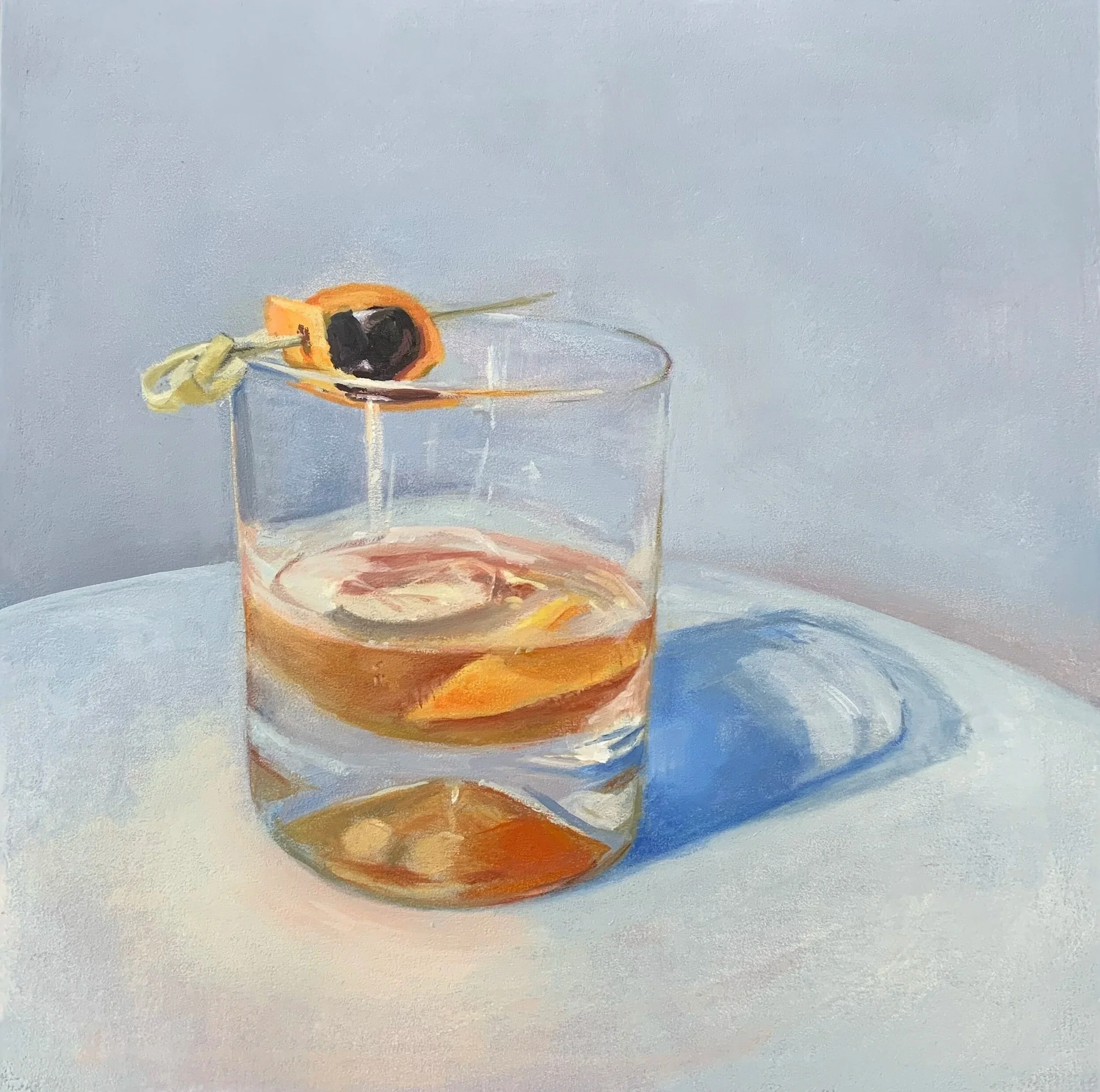 A glass of amber-colored liquor with ice cubes, placed on a white surface, with a lemon twist and black cherry garnish on the rim.