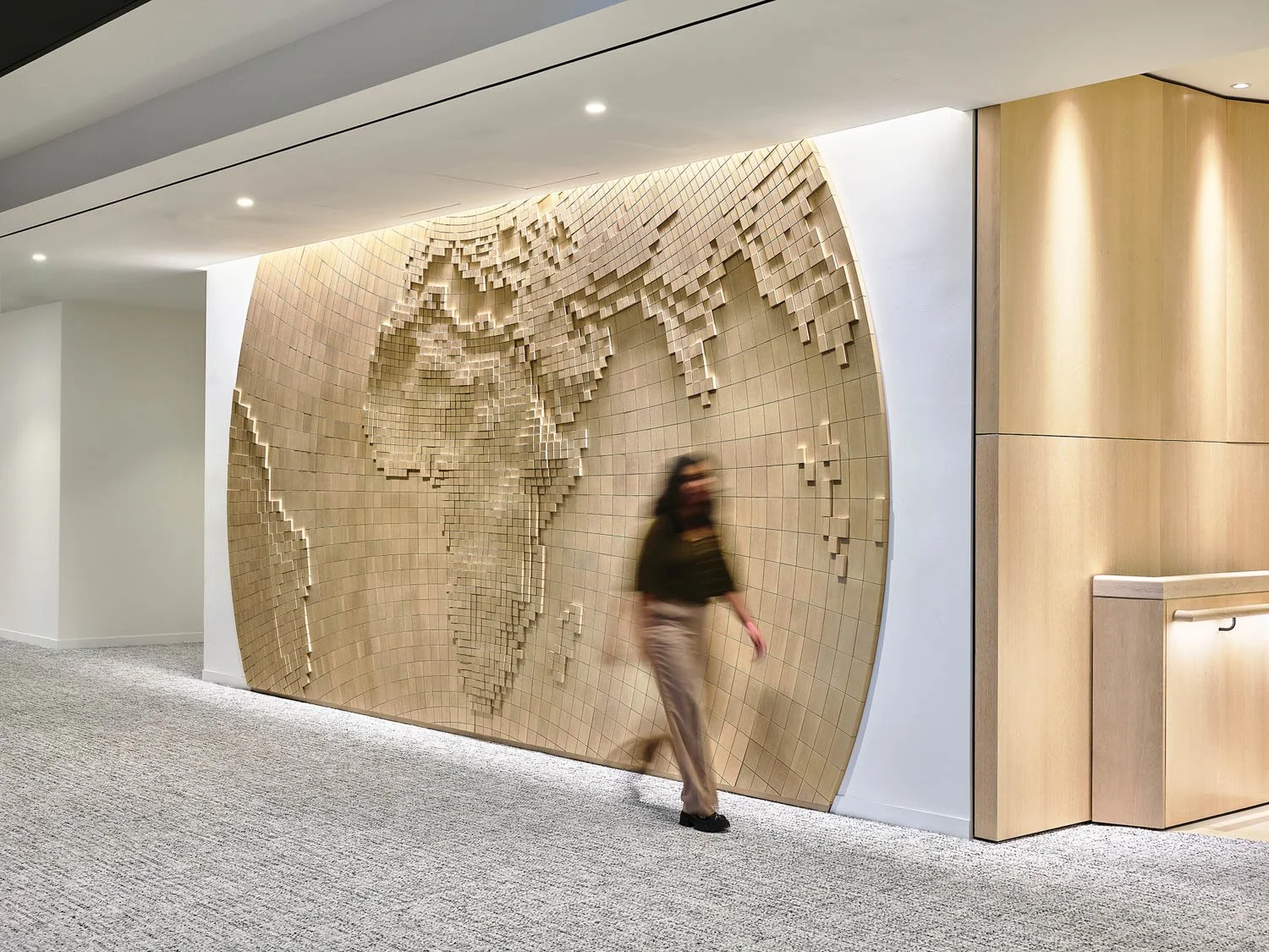 An interior office space with a full-height, 3D wooden map of Africa mounted to the wall.