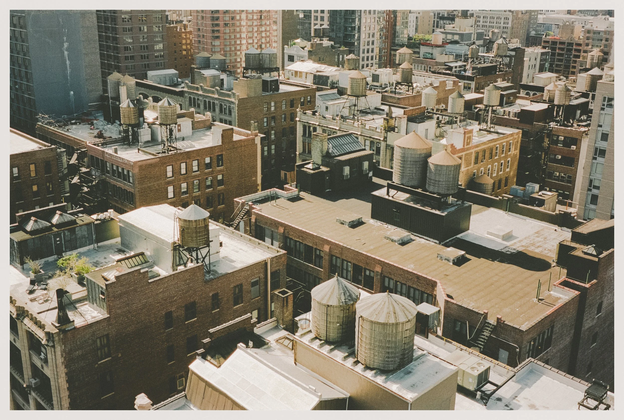 View of city rooftops with water towers and various building types in a dense urban area.