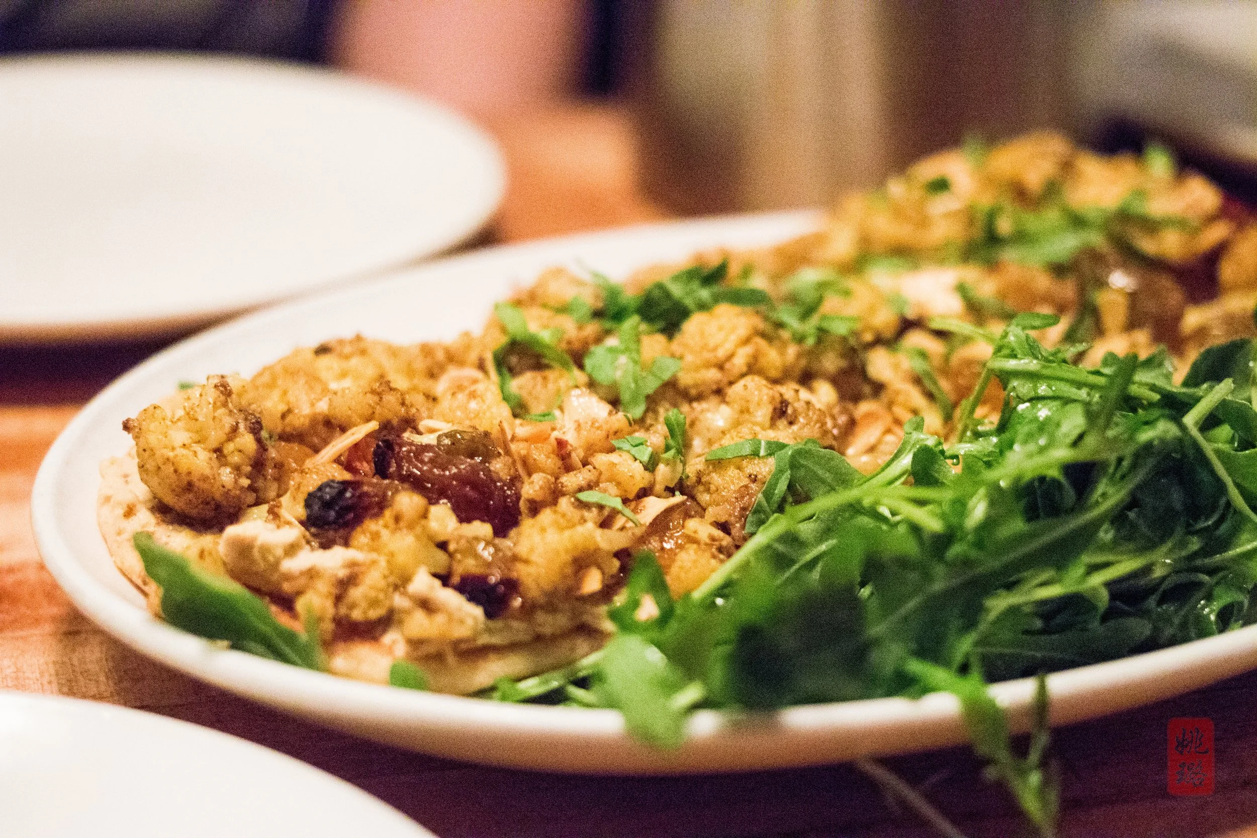Cauliflower tartine: curry-roasted cauliflower, hummus, golden raisins, toasted almonds, and parsley on toasted naan