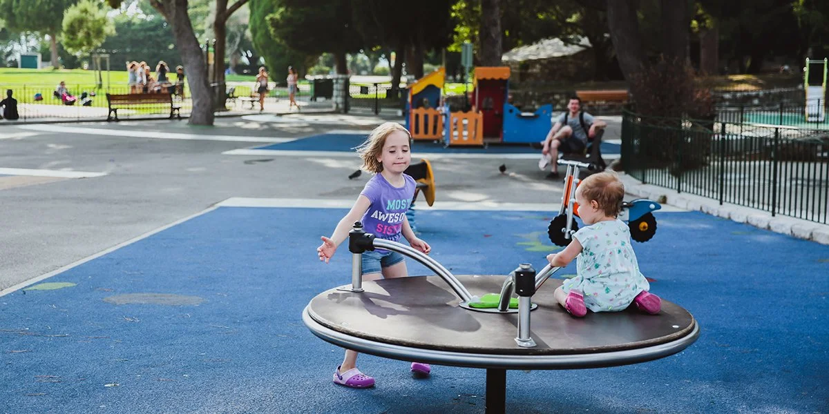 two happy sisters playing on the playground