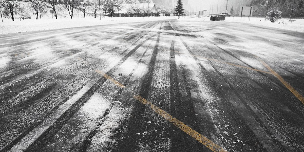 snow covered parking lot with yellow parking lines showing through