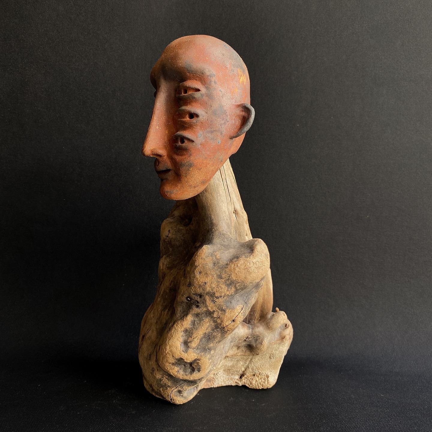  The ceramic head replicates this natural process just as wood weathers and takes on an exquisite form through years of exposure. The saggar technique introduces oxides, pigments, and leaves, mirroring nature's unpredictability and yielding a surface