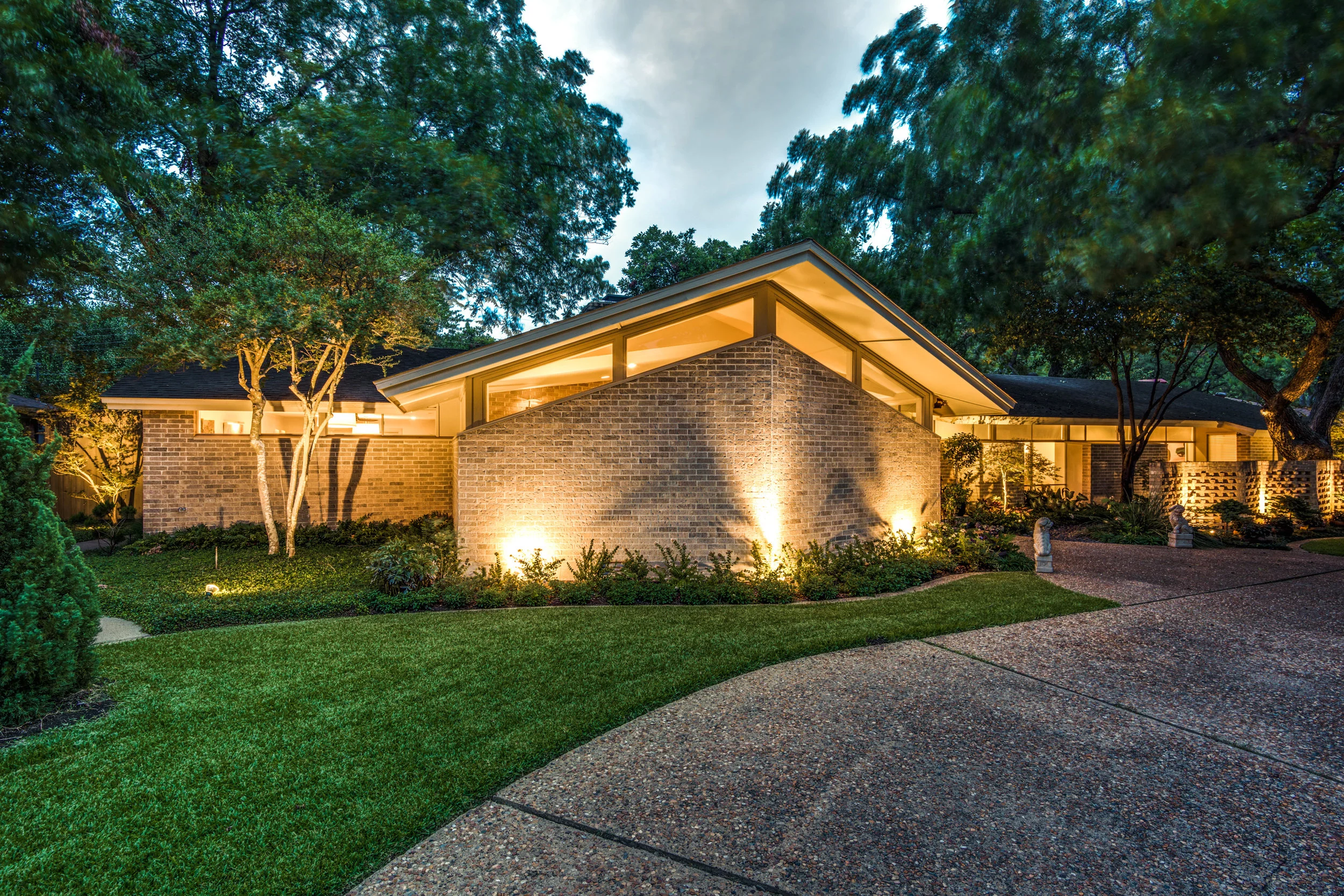 1327 Bar Harbor Drive, Dallas, Texas 75232 A grand drive up with a sleek and sexy appeal, this 1967 mid-century stunner designed by architect John Thompson has been gracefully transitioned to embrace the admired design of the era. In fact, the authenticity of the home scored it a feature on the 42nd Old Oak Cliff Conservation League Home Tour in 2015. The 3,500-square foot home integrates open spaces and brings the outdoors in. Three large mountain Junipers perfectly perched in front frame the facade of the home and balance the small Zen garden that is artfully tucked behind the perforated brick screen wall. Subtle lighting gently cascades down on the waterfall completely visible from the interior. The best way to diminish the value of a mid-century home is to diverge from the aesthetics of the era. Thankfully, this one was updated with educated precision. The home boasts a wonderful curb appeal with its bold turquoise period front door and dramatic angles. The entry shows original brick flooring and opens to a tucked in seating salon (which could also be a dining area) carefully lit with a sputnik chandelier. The living room’s vaulted ceiling, elongated brick fireplace, and transom windows preserve the mid-century drama of this home. This classic style extends to the gourmet kitchen complete with custom sleek mahogany cabinets and a marble island. Off of the main kitchen, find a clean, white catering kitchen featuring a commercial grade beverage refrigerator, deep stainless-steel sink, and ample storage—ideal for the ultimate entertainer. Visible through the glass doors of the den, the home also showcases a spectacular Zen garden, complete with multiple waterfalls and a mature pecan tree sculptured with Mondo grass for total harmony. To the right, a sun-room looks out onto the Zen yard to add a tranquil, chic spot to meditate. Off of the entry to the private quarters is a dramatic hallway with floor-to-ceiling windows looking out into the front rock garden, which is peppered with Japanese maples and harbored by a perforated brick wall. Each of the four bedrooms have en-suite bathrooms, and, notably, the master bath has separate lavatories nicely divided by a marble frame-less shower and walk in closets on each side. The spacious master bed additionally features an off-master seating area with an original light fixture that exemplifies the striking geometric style of the mid-century era. Through the double glass doors, wake up and gaze into the grassed backyard decorated with two large urns overflowing with greenery and another beautiful water feature. Bar Harbor is a winding street of architecturally interesting homes nestled under towering trees and located across from the Oak Cliff Country Club. This hidden gem, tucked away in beautiful Wynnewood Hills, rivals the best mid-century modern homes in Dallas. The home has been cleverly integrated with nature using ample windows and multiple areas of soothing, ambient lighting. 1327 Bar Harbor Drive will curb the carvings of any MCM aficionado. The current owner installed one 5-ton and one 4-ton Trane HVAC unit in July of 2016. The home has a two-car garage with ample storage that opens to a rear driveway. All notable light fixtures will convey with the property, with exception to the Lalique wall sconce in the entry. Additionally, the two oversized urns with foliage will convey. 