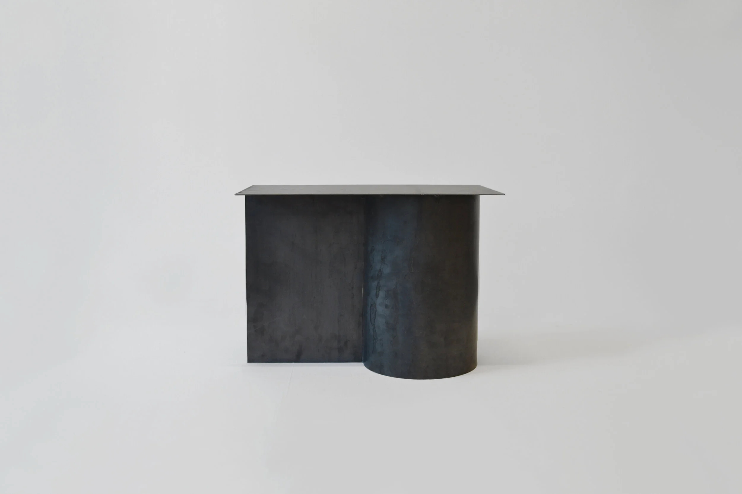 CARA \ DAVIDE Editions | Calandra | Custom Side Table | Aybar Gallery Unique side table exploring rolled sheet metal, the process of calendaring, patinas and shape. The object is characterised by a cylindrical leg and two planar surfaces; one vertically intersecting the leg and the other resting on top.⁠ ⁠ Handmade in Milan, Italy by expert artisans. Welding marks are testament to the skilled craftsmanship that goes into each unique piece.⁠ ⁠ Carefully selected raw iron with natural patina. ⁠ Matte waxed finish.⁠
