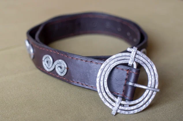 S-shaped sauce pans on belt with a spiral buckle. Aluminium or brass. Variable sizes.
