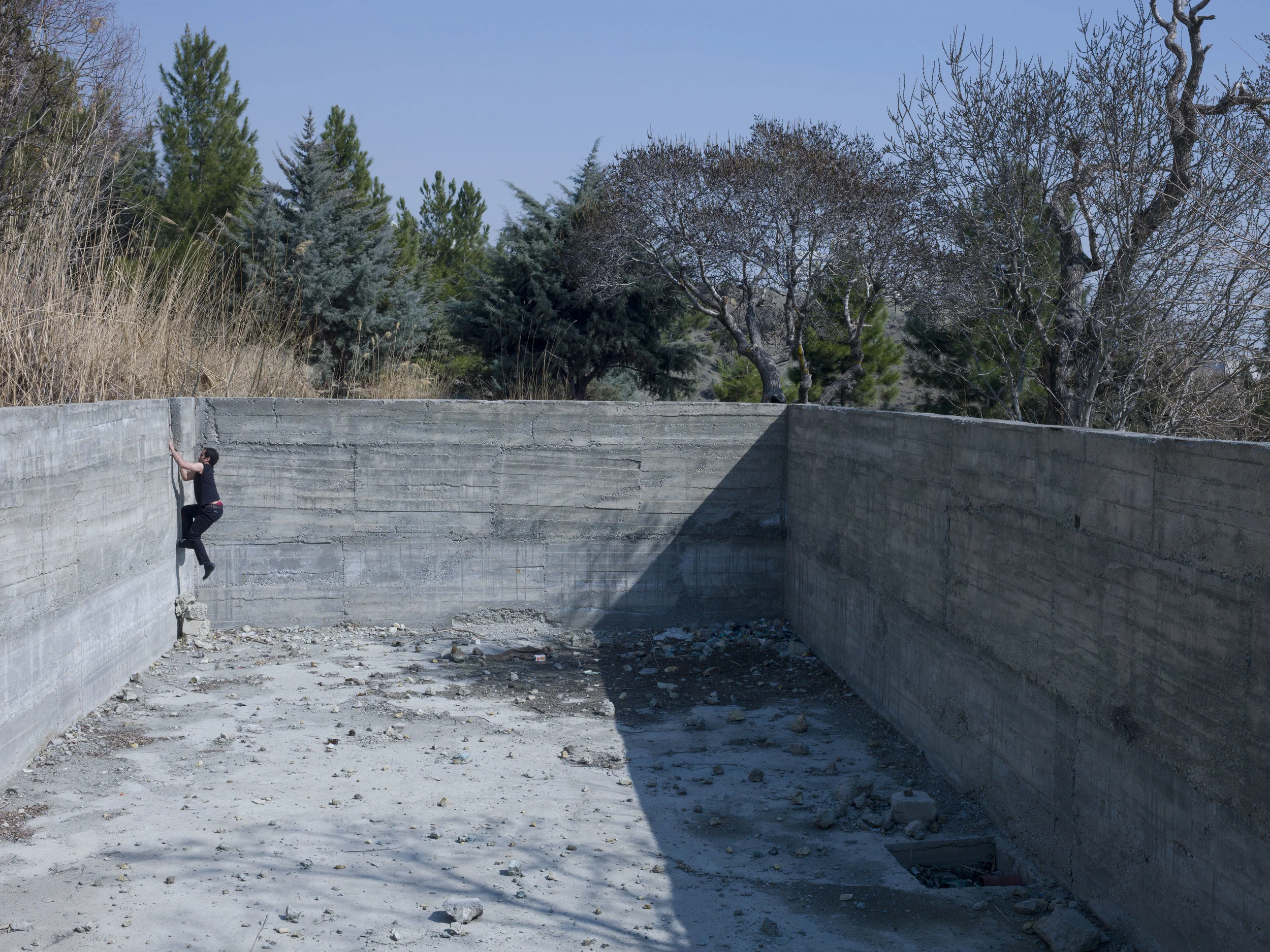 Image above: ©Newsha Tavakolian, IRAN. Teheran. Mahud, climbing the wall of the abandoned empty swimming pool, which is the only quiet place he can find to practice his singing. 2014 / Courtesy of Magnum Photos