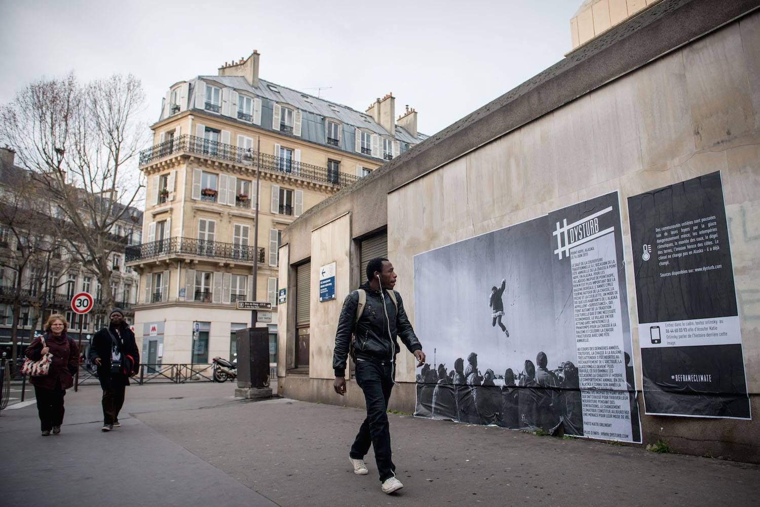 ©Benjamin Girette. For COP21, we teamed up with the Magnum Foundation, Yale School of Forestry and Environ-mental Studies, NYU-ITP Students & Twillio to #reframeclimate by pasting current photojournalism in the streets of Paris. Pictured is Katie Orlinsky's photograph that was pasted in Paris. The caption reads: The traditional blanket toss at the annual whaling feast in Point Hope, Alaska on June 16, 2015. For the Inupiat villagers of Point Hope, nothing is more important than the bowhead whale. The calendar year revolves around hunting, fishing and gathering, a lifestyle Alaskans call “subsistence,” which is as much cultural tradition as economic necessity. The entire village looks for-ward to spring whaling, and celebrates a successful hunt with an annual feast. In recent years, however, the much-anticipated whale hunt has run up against a warming Arctic. Ice is getting thinner, windows of opportunity for hunting are shrinking and animal behavior is changing. Alaska had its hottest year on record in 2014, and for Inupiat villagers in Point Hope who have hunted and foraged their meals for generations, climate change now threatens their way of life.