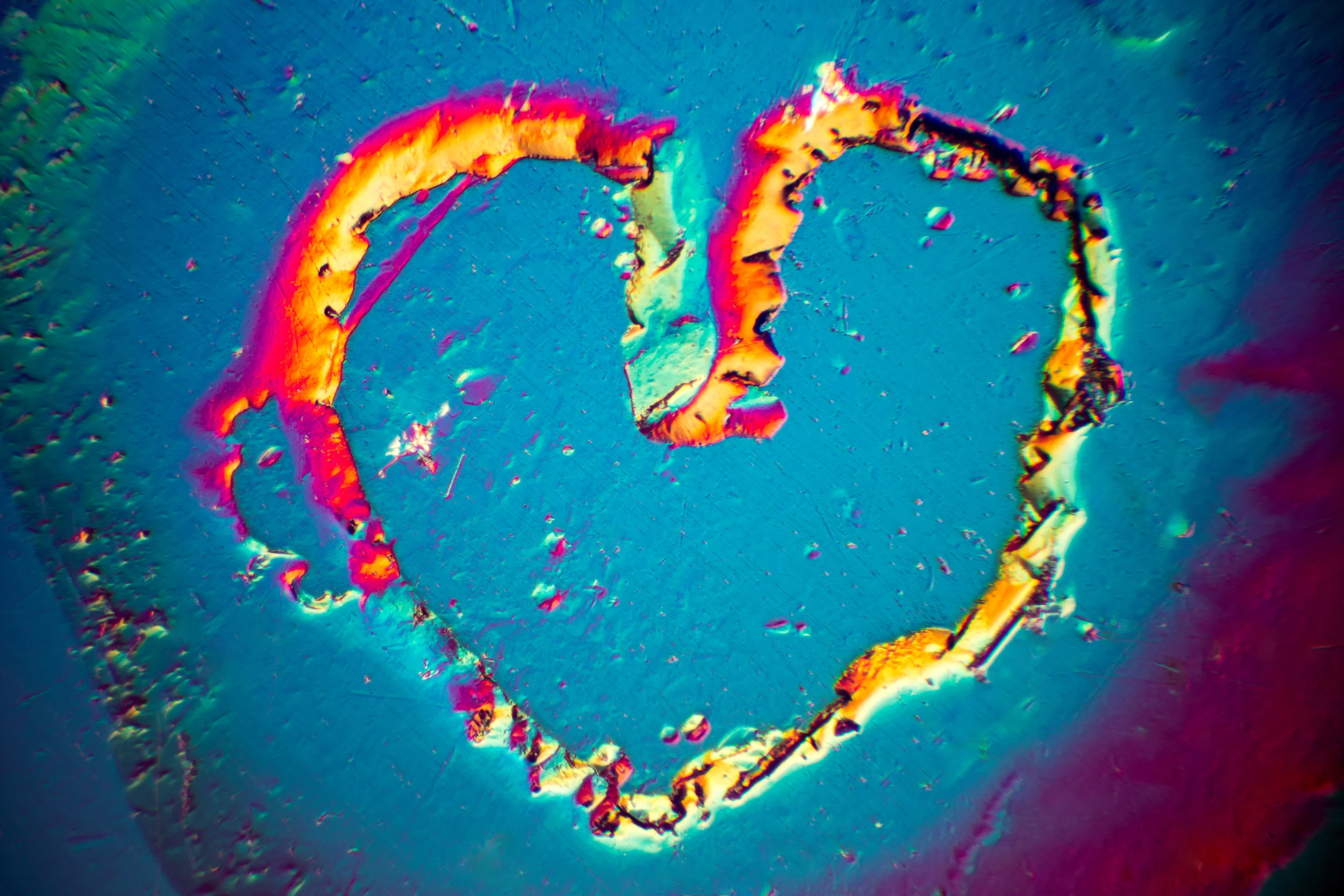 A natural heart shape etch feature was present on the surface of a beryl crystal. This image was taken using differential interference contrast microscopy. The horizontal field of view is 1.1mm. © Nathan Renfro