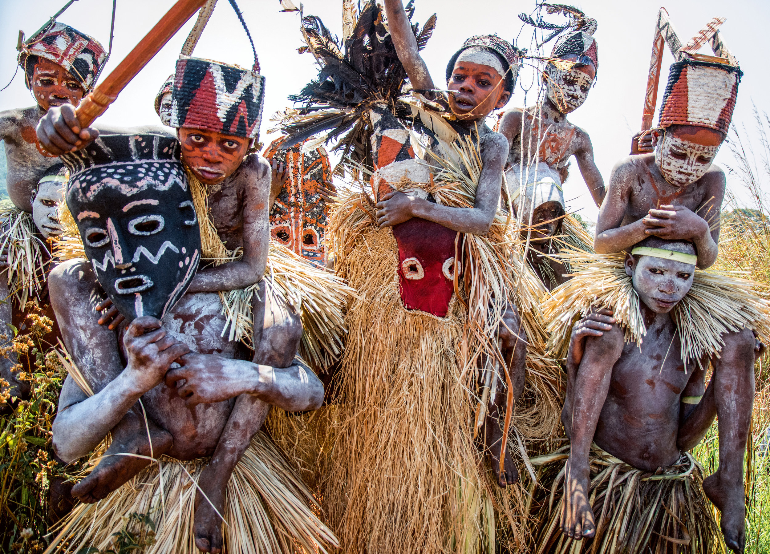 Shields made of wooden slats and decorated with ocher, chalk, and charcoal are carried by the older initiates, who lead the younger boys across the field in the direction of the village. The boys are carried on the shoulders of their masked mentors back to the village, where they will be reunited with their families. © African Twilight: The Vanishing Cultures and Ceremonies of the African Continent by Carol Beckwith and Angela Fisher, Rizzoli, 2018.
