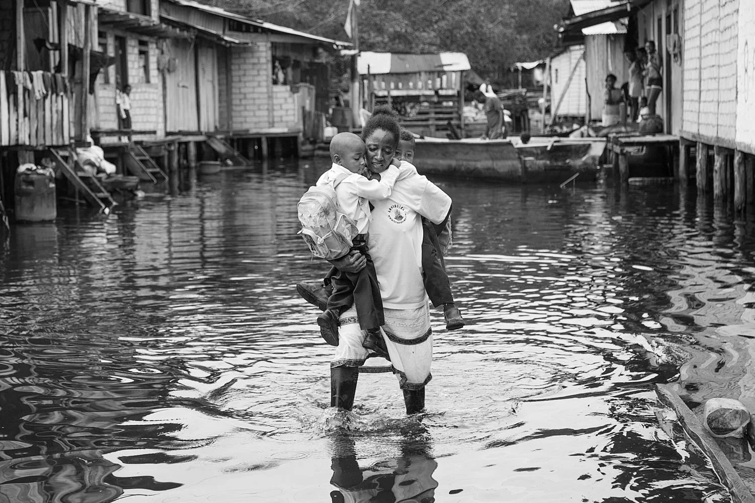 Rosa Quiñones carries her sons Efraín and Isac to school during the monthly high tide that floods the communities of the mangrove for several days in a row. The communities in the Cayapas Mataje Mangrove Reserve have absolutely no sanitation as the tides flood any kind of improved facilities. Tambillo, Ecuador. 2014