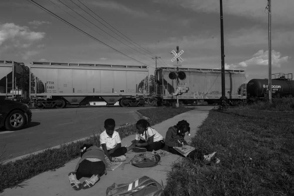 For more than two hours, a stopped freight train blocked an intersection on the border between Riverdale and Dolton in the south suburbs. Trying to get home after school, children began to do their homework as they waited for the train to clear. © Sebastián Hidalgo