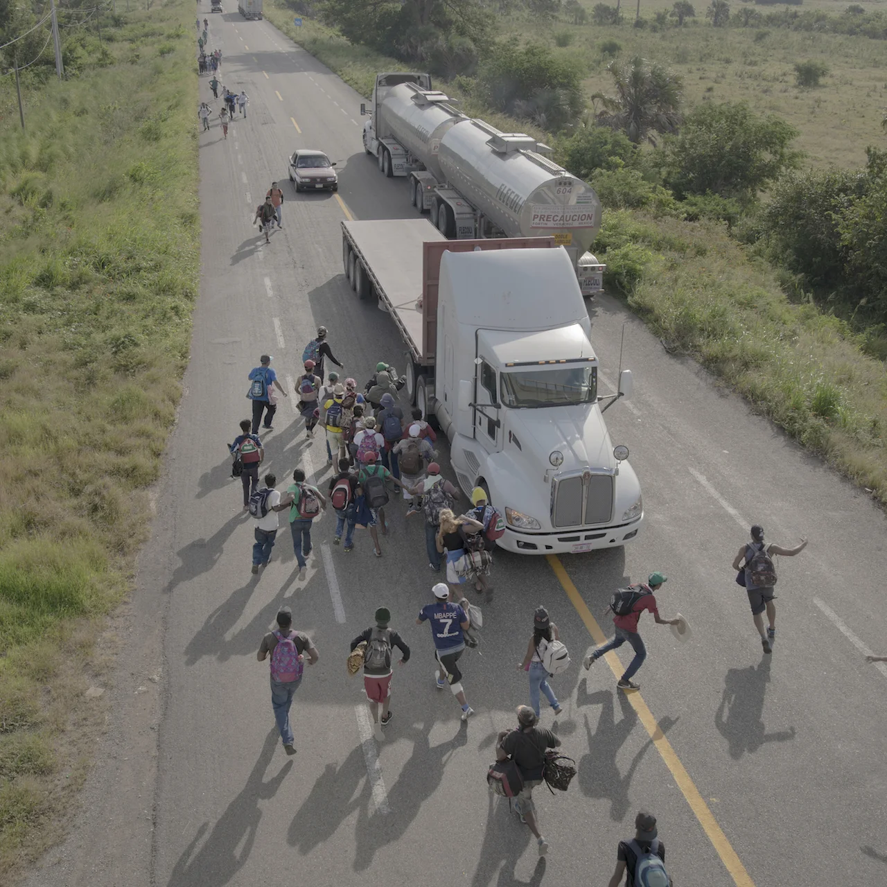 People run to a truck that has stopped to give them a ride, outside Tapanatepec, Mexico, on 30 October 2018. Some drivers charged to give travelers a lift for part of the way, but most offered services free as a sign of support. © Pieter Ten Hoopen, Agence Vu/Civilian Act