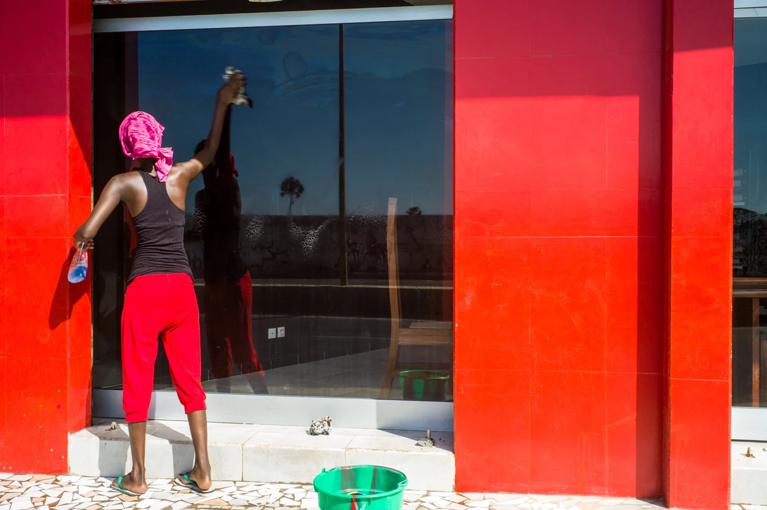 A woman cleaning a shop window in Dakar. © Werner Mansholt