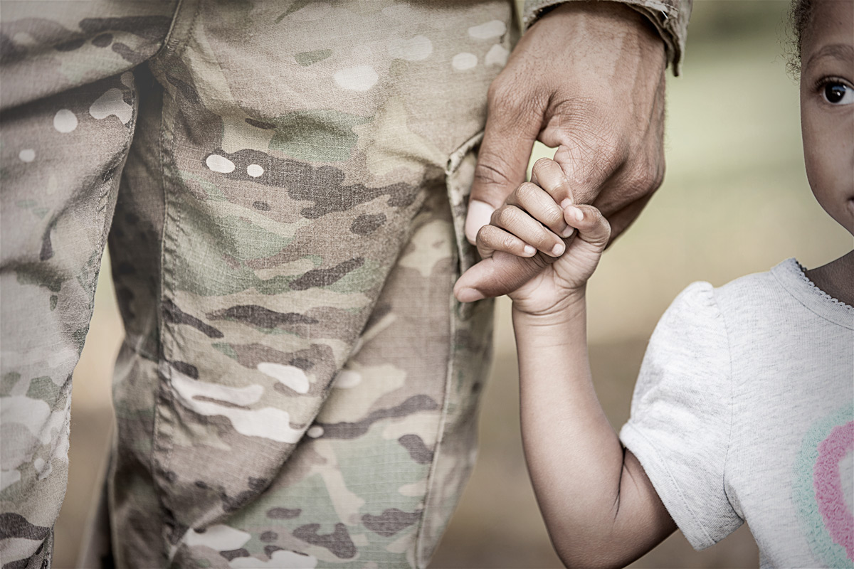 Image of veteran in uniform holding a young childs hand