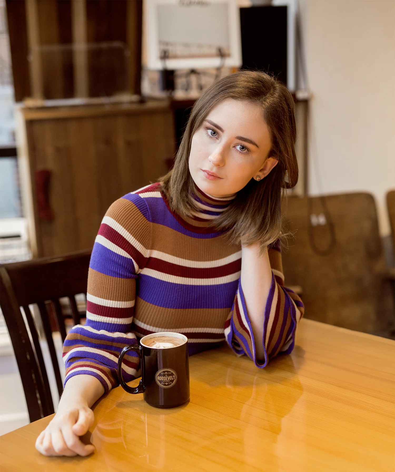 Girl sitting at a table posing inside roosevelt coffeehouse on long street in columbus, ohio