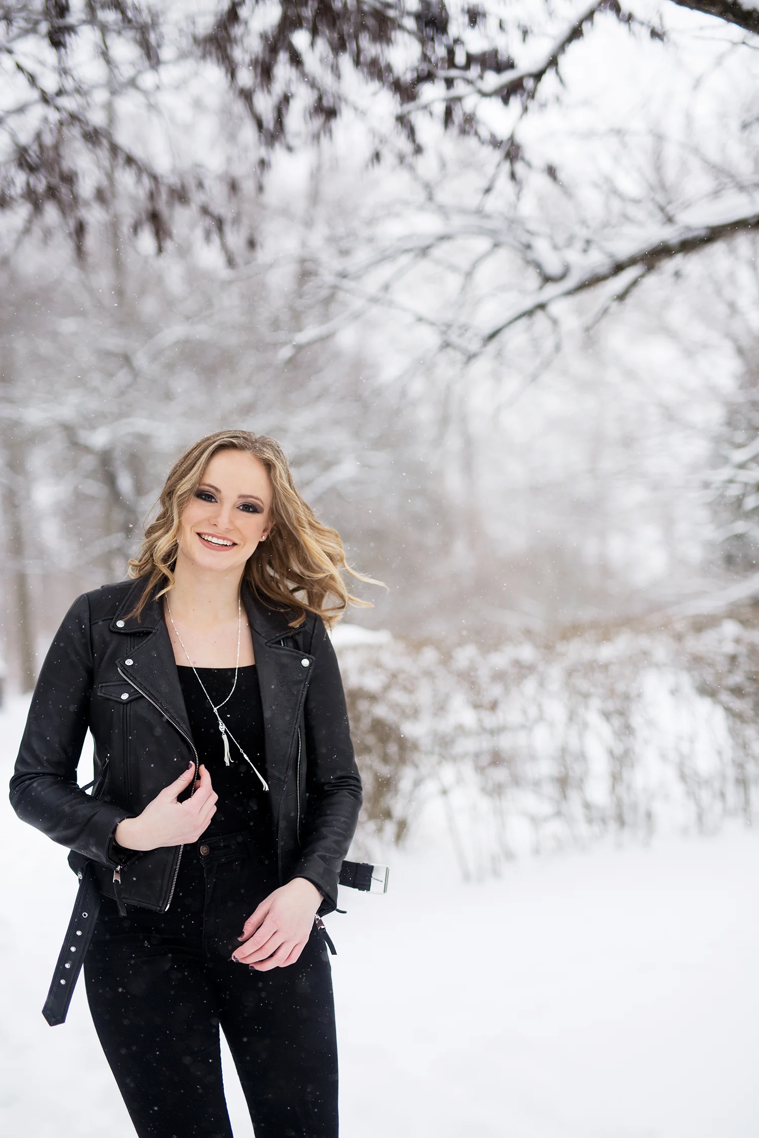 a girl in all black smiling in the snow.