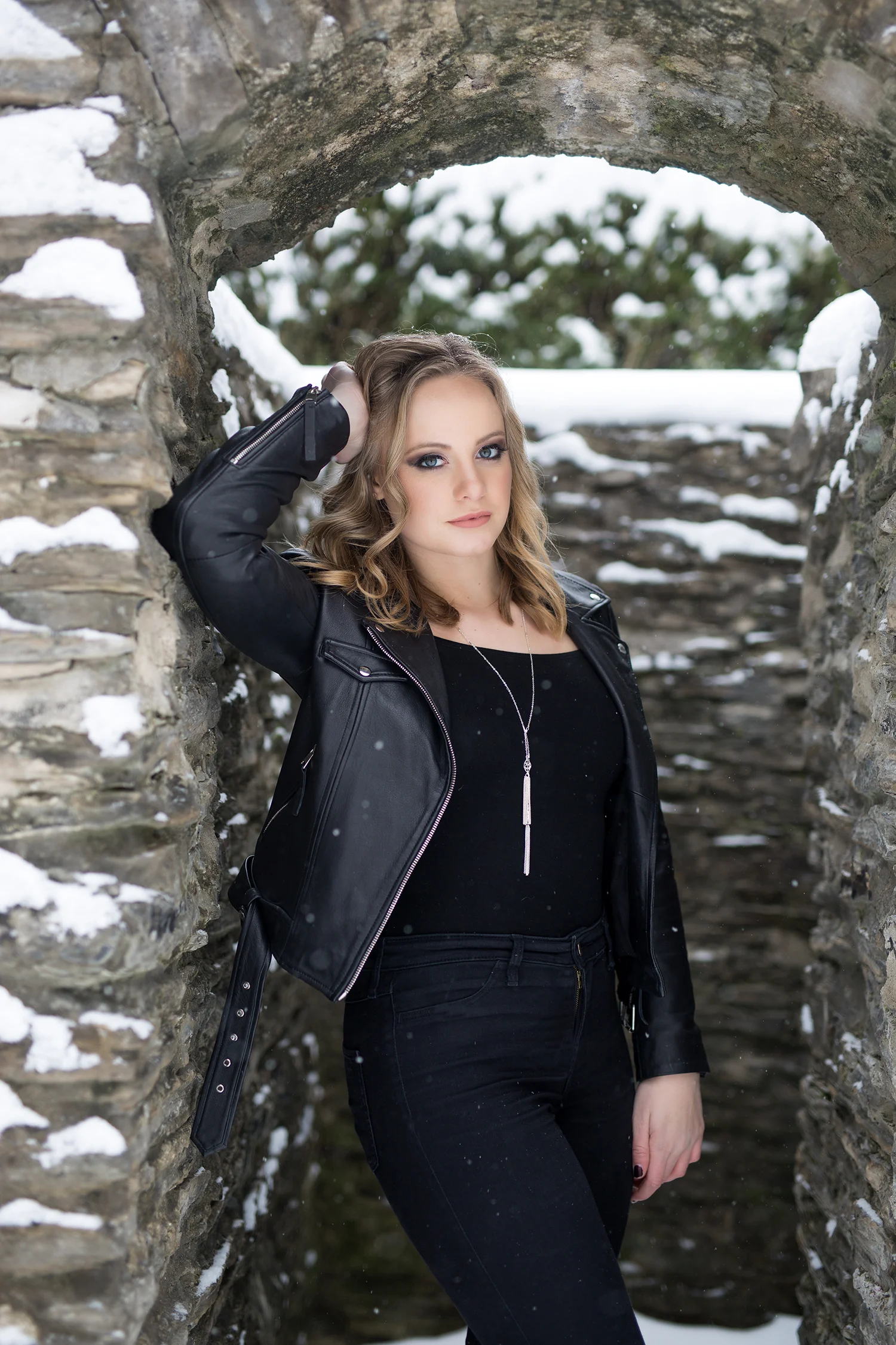 a girl in all black posing against a stone arch way in bexley, ohio.