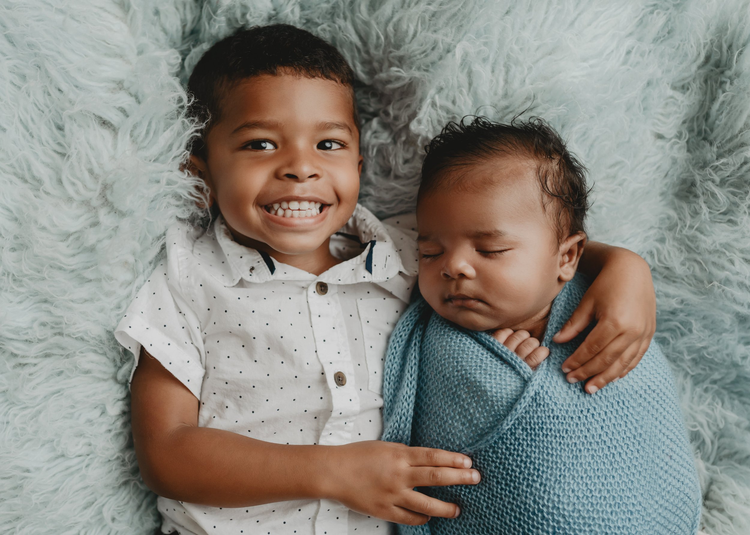 Newborn baby boy with brother on flokati 