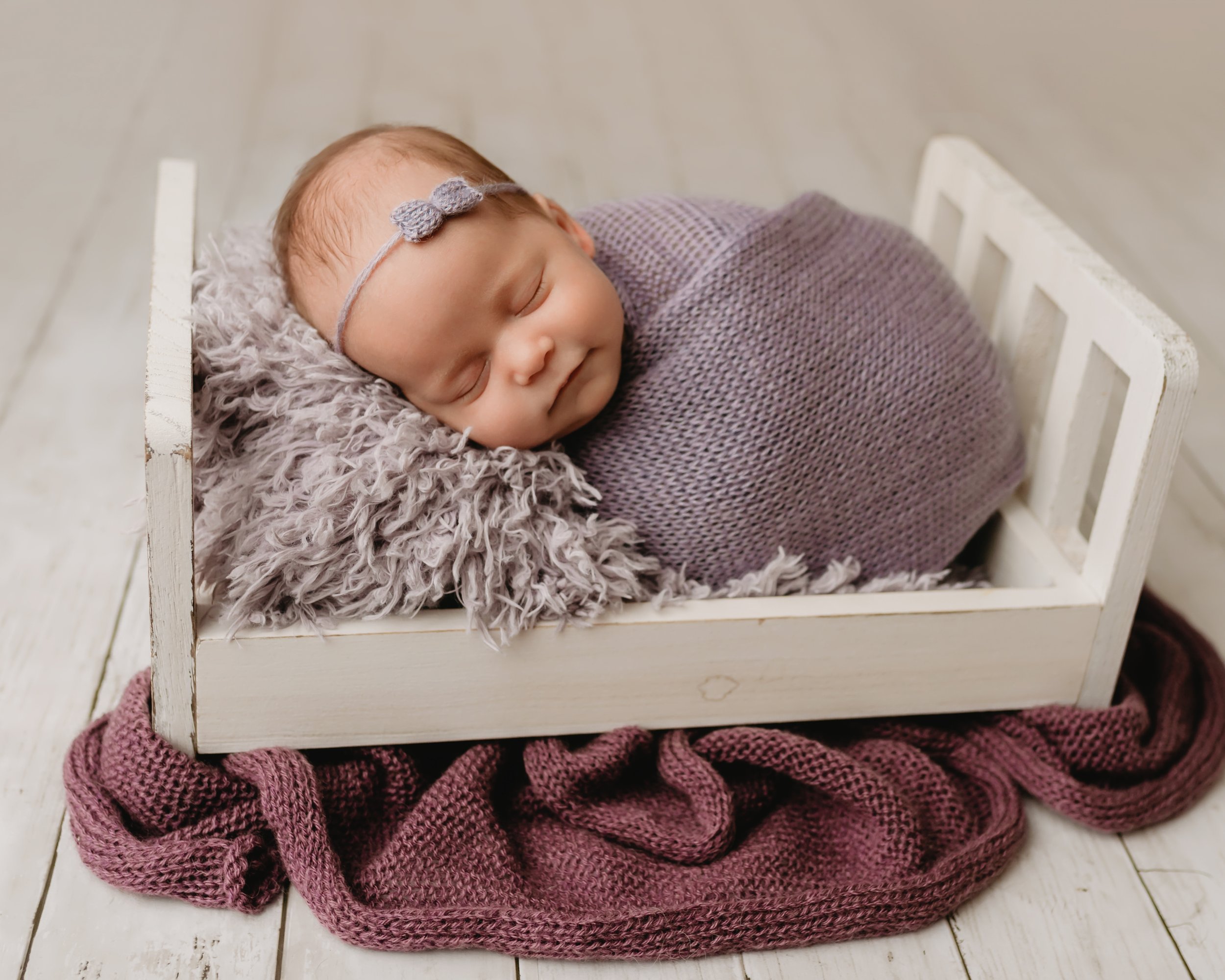 Boca-Raton-Newborn-Photographer-Baby-in-purple-wrapped-in-bed