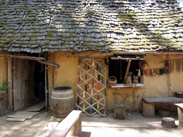 The dyer's cottage at Guédelon. Dyed threads hang out front. The roof is hand-shingled with rough hewn strips of wood with the bark still attached.