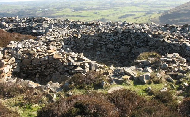 To help with imagining what a hill fort looks like: The remains of a hill fort in Gwynedd, Great Britain. Round hut bases at the SE end of the Tre'r Ceiri hill fort cc-by-sa/2.0 - © Eric Jones - geograph.org.uk/p/690634