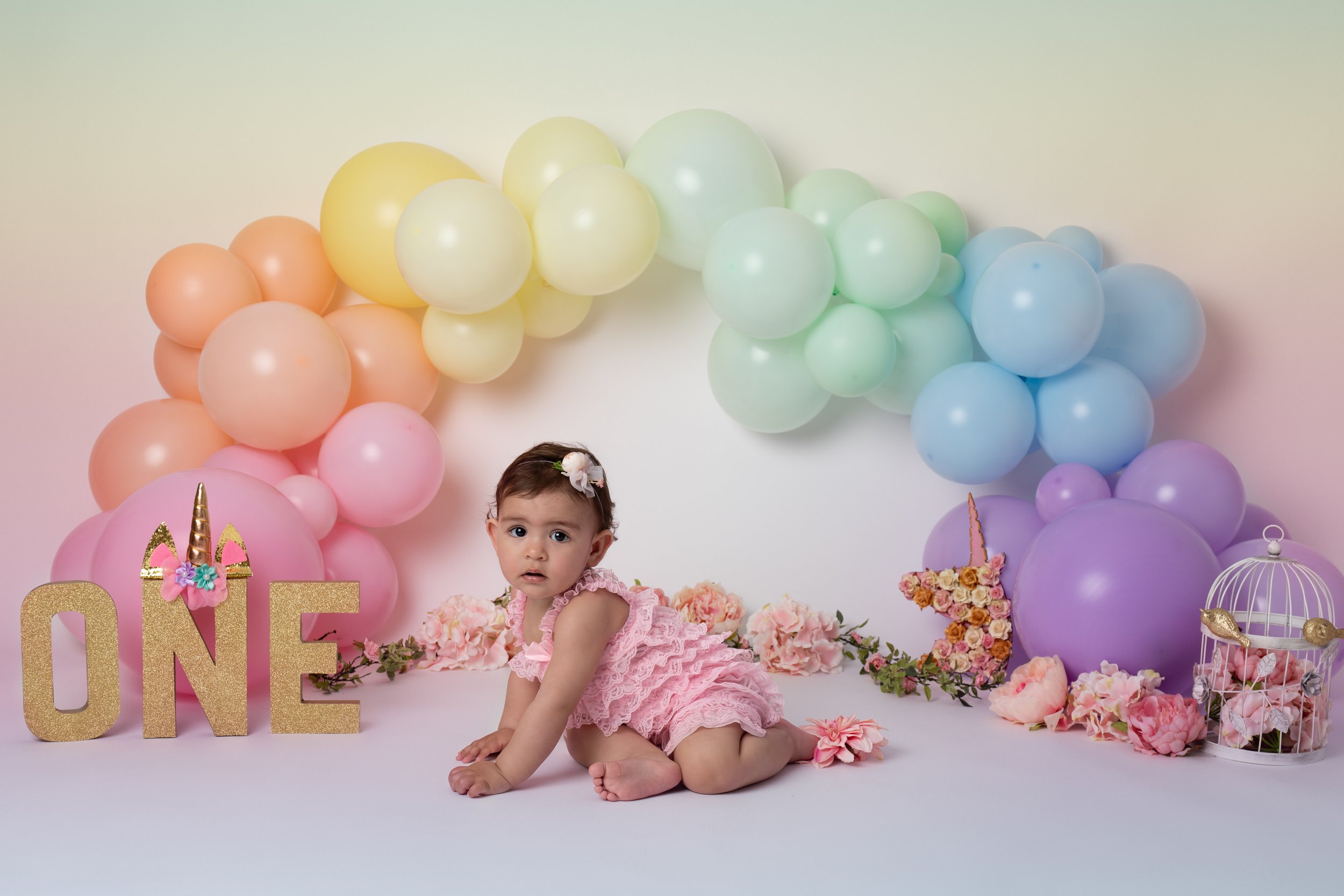  one year old girl with rainbow balloons in cute pink outfit in Northampton studio 