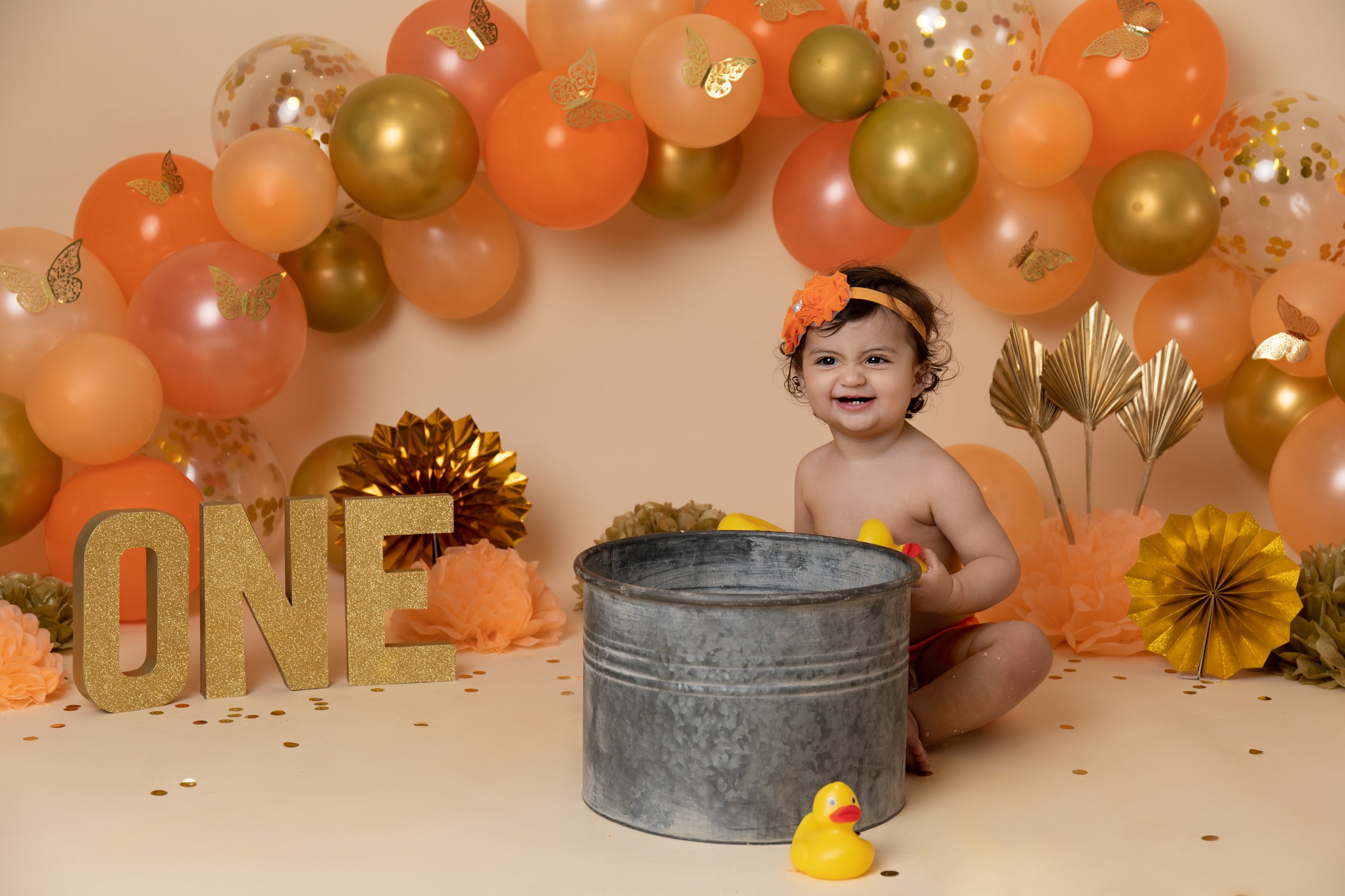 One year old girl with orange balloons playing with rubber duck in Buckingham studio 