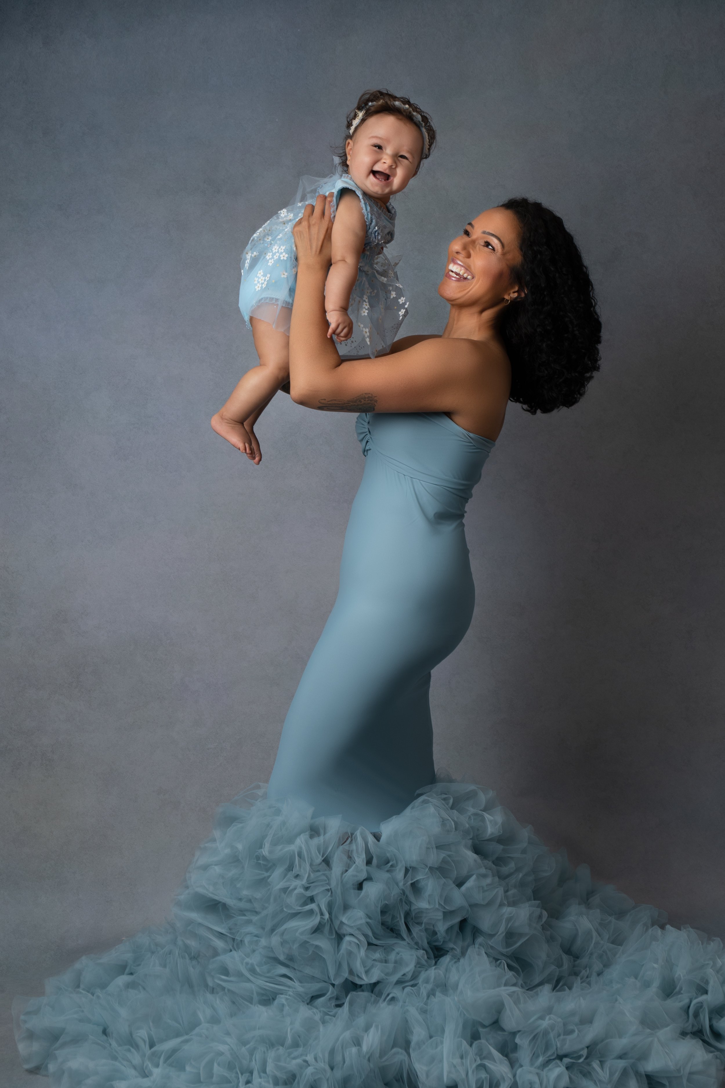  Mum wearing beautiful blue dress holding her baby girl in Milton Keynes studio  