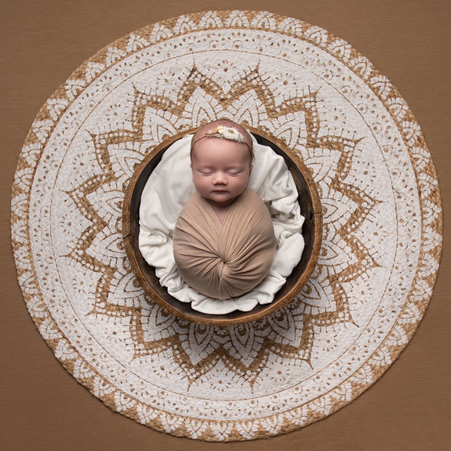 Newborn baby girl with a floral headband asleep on a mandala backdrop, by Jitka Wenham Photography, Milton Keynes