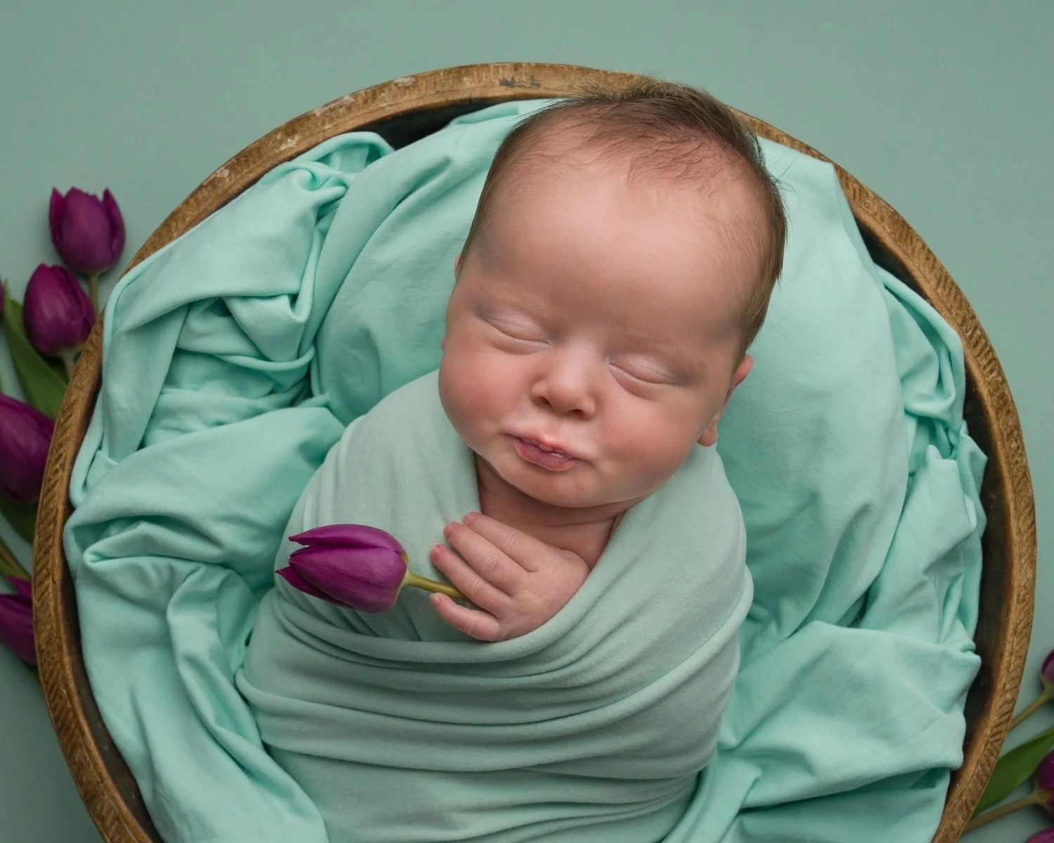 Close-up of a sleeping newborn baby wrapped in mint green, photographed in the first weeks by Jitka Wenham Photography, Milton Keynes