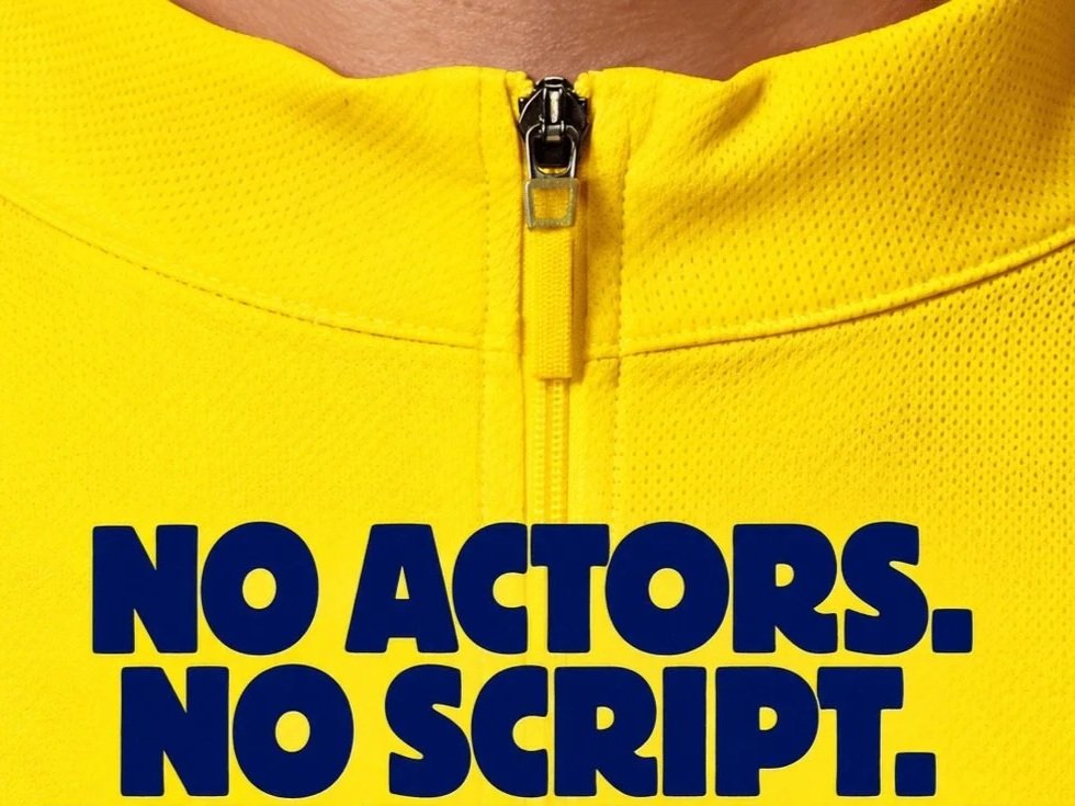 Close-up of a yellow cycling jersey with the Tour de France campaign line “NO ACTORS. NO SCRIPT.”