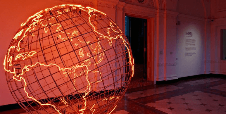 Orange-lit globe sculpture inside the Royal Academy of Arts exhibition space.
