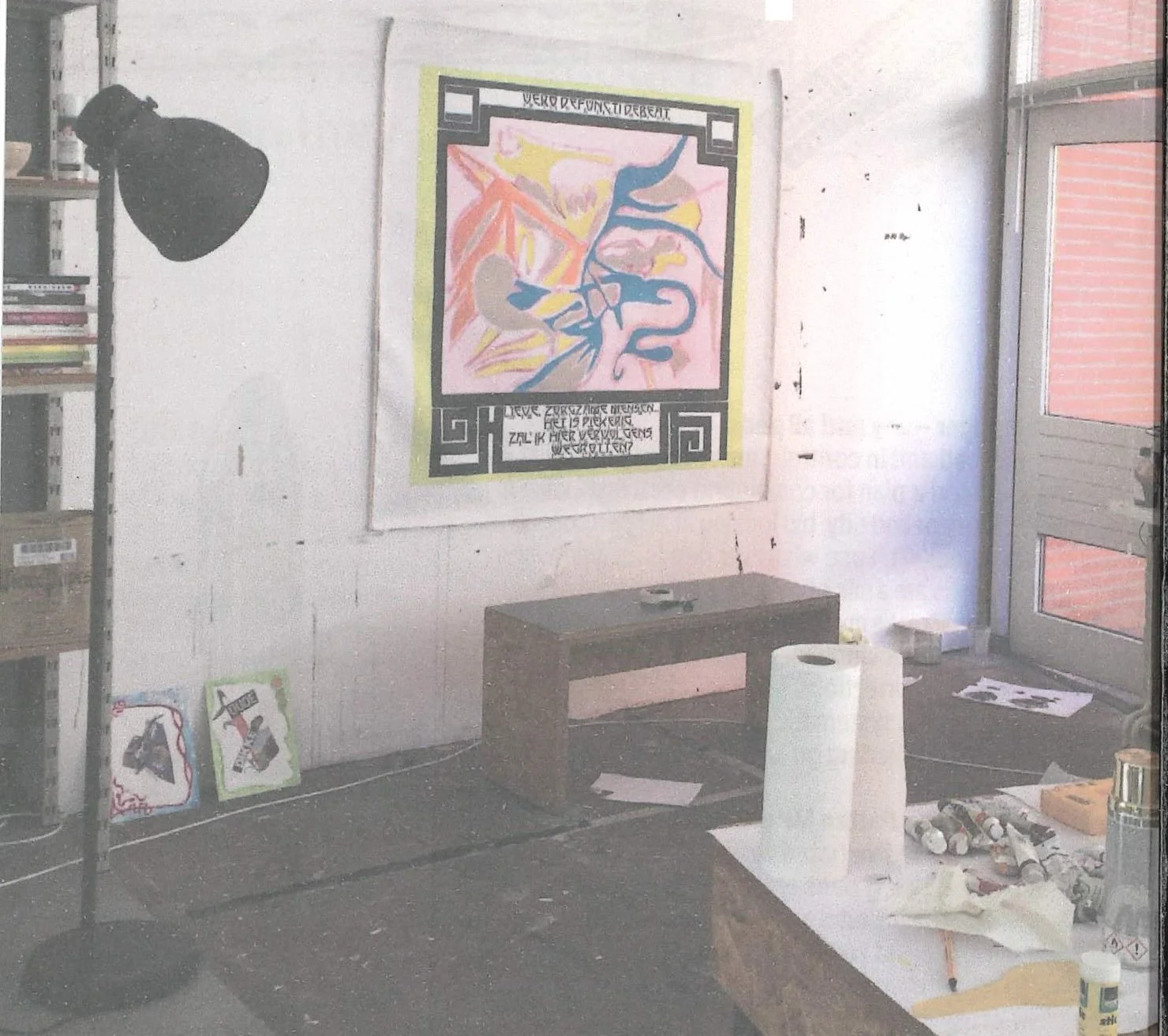 A studio space with a painting on the wall with paints on tables