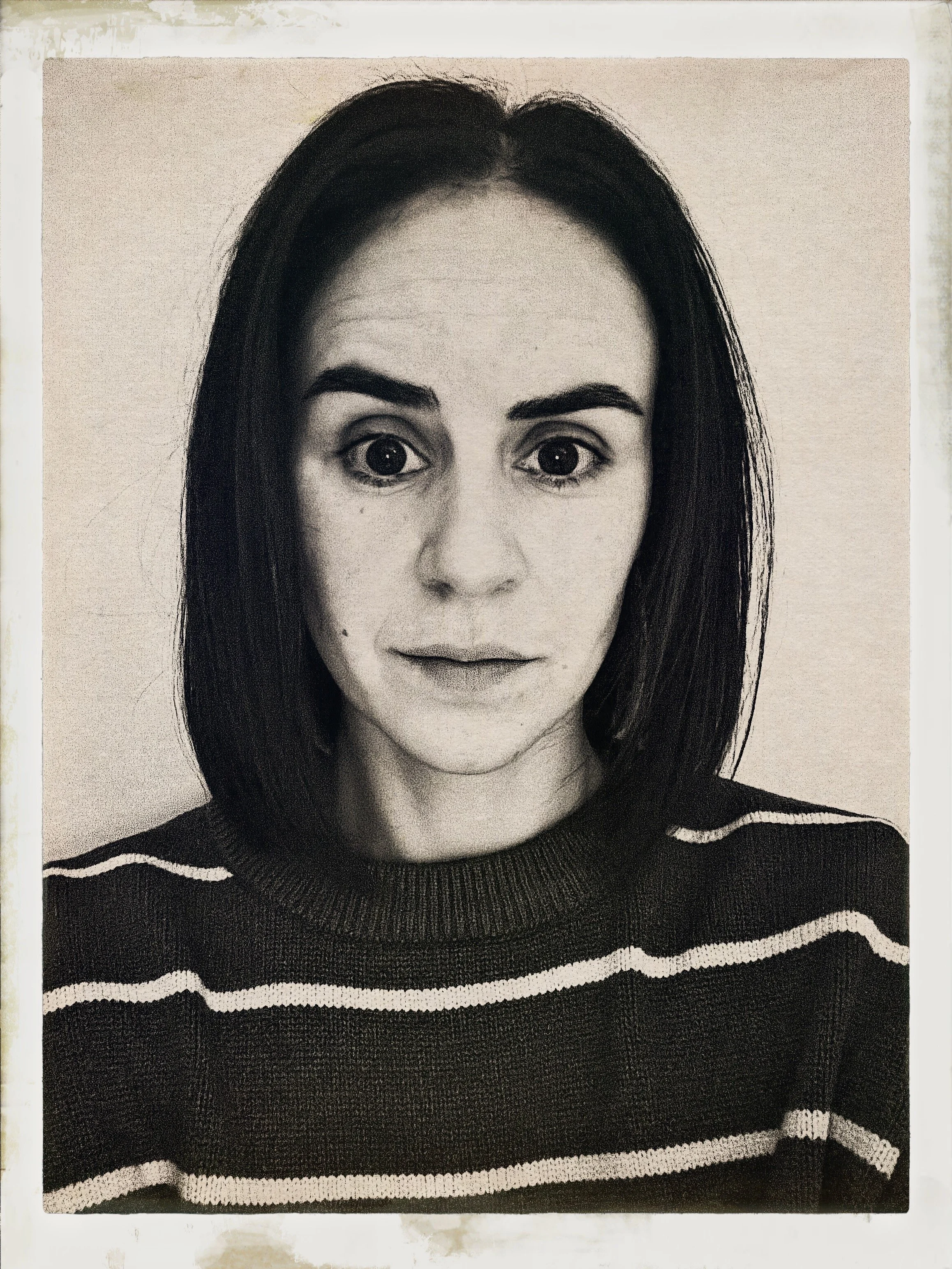 Black and white portrait of a woman with shoulder-length dark hair, wearing a striped sweater, looking directly at the camera.