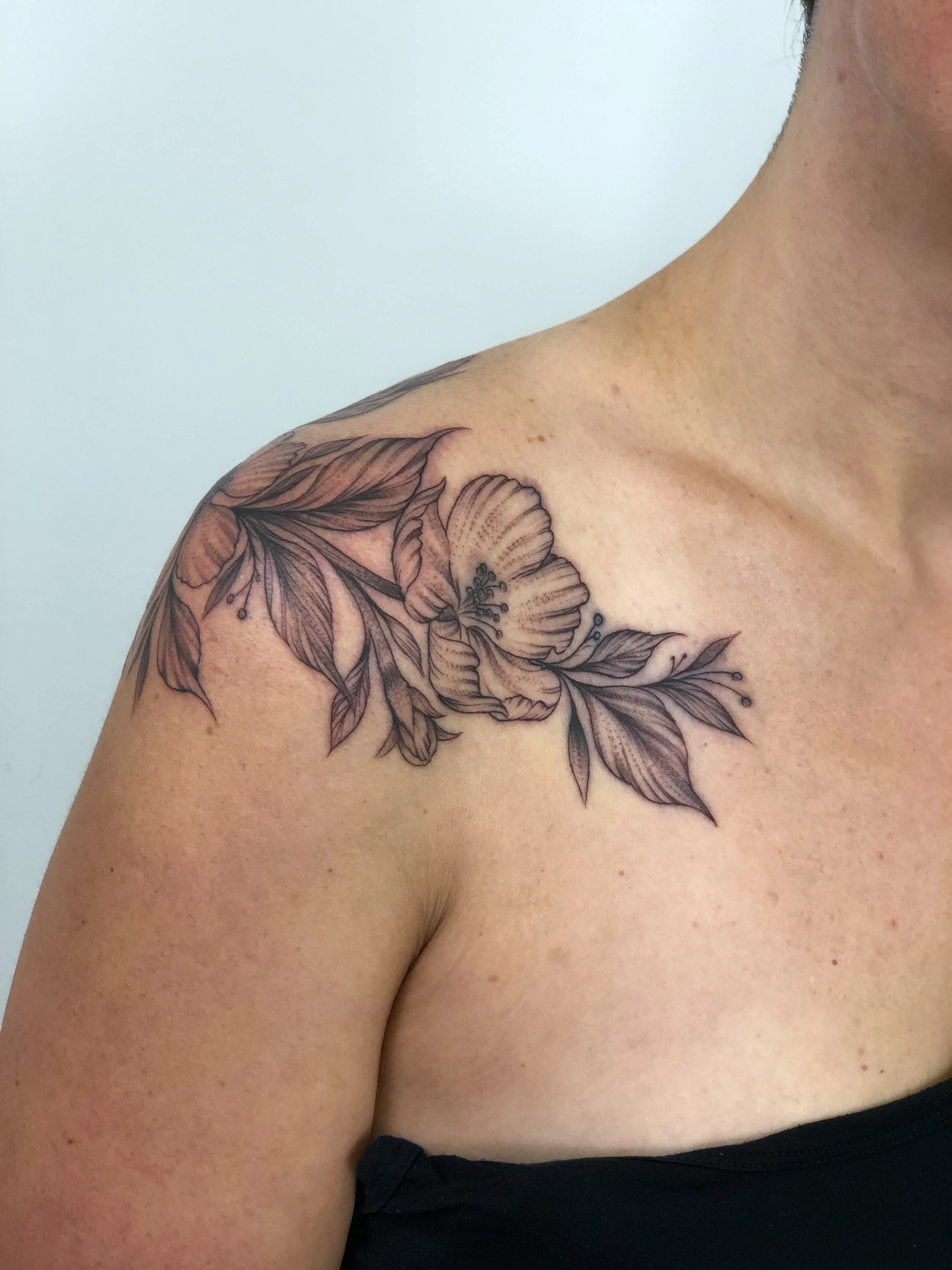 Fineline Blackwork Floral Tattoo with leaves on shoulder