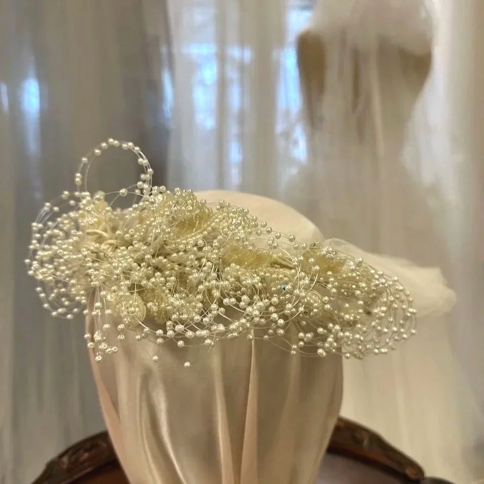 1990 bridal headpiece with beaded sequined leaves and loops of pearl filaments.