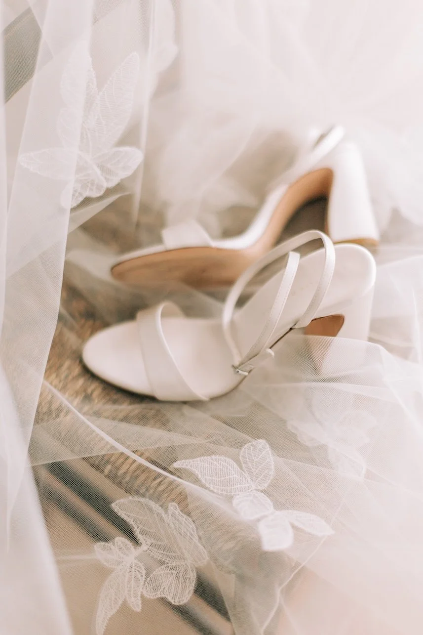 Close up portrait of wedding veil leaf lace embroidery with white bridal shoes placed on top.
