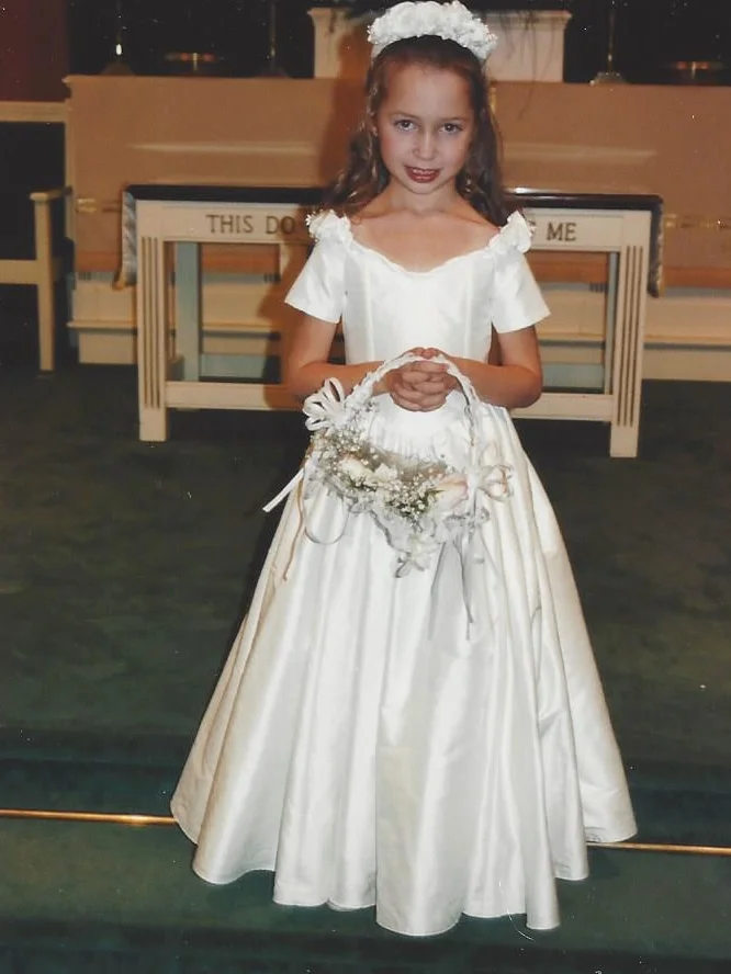 Brielle was a flower girl in 1995. Her silk duppioni dress was designed to match her cousin's wedding gown silhouette. Hand gathered silk petal flowers adorned the dress.