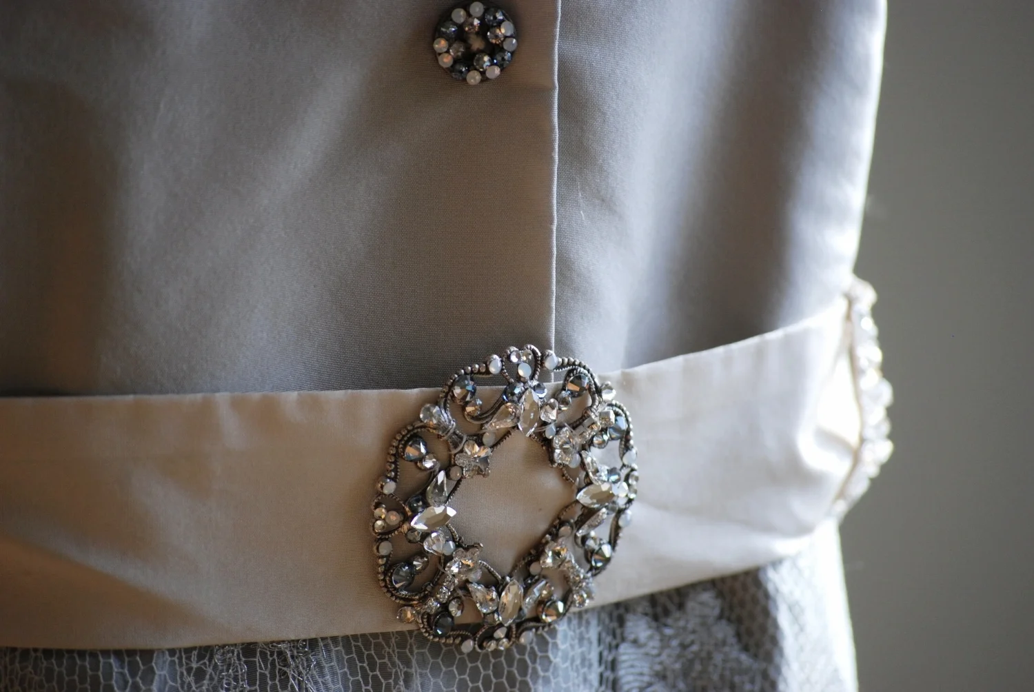 I wanted a Jackie Kennedy style with a menswear influence. I handmade the buttons and belt buckle The soft toned palette of gray, ivory, and taupe was in my mind from the beginning. My skirt was made of iridescent silk taffeta with a metallic silver and ivory French lace overlay. I loved everything about it!