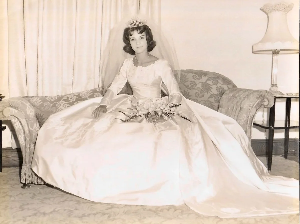 Black and white 1960 wedding portrait of bride wearing satin wedding gown and tall crystal headpiece with veil.