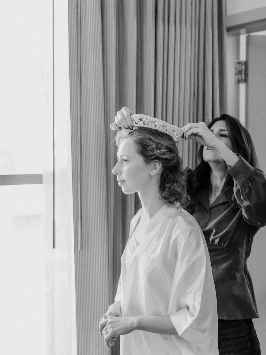 Mother of the bride placing grandmother's bridal crown on granddaughter on her wedding day.