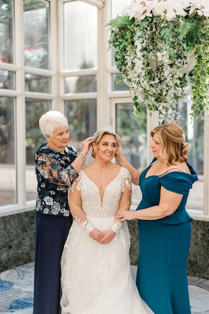Grandmother, granddaughter, and mother of the bride placing their vintage family wedding crown on the bride on her wedding day.
