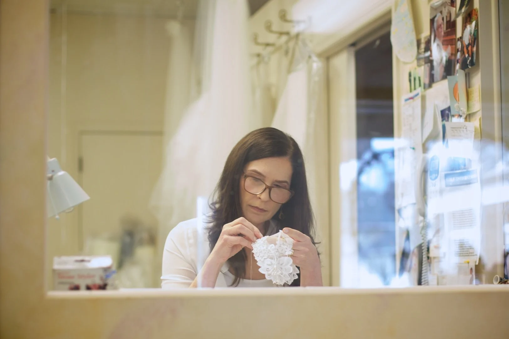 Marie Hunt, designer and owner of Headpiece.com working at her desk hand sewing pearls to restore a 1970s vintage Juliet cap.